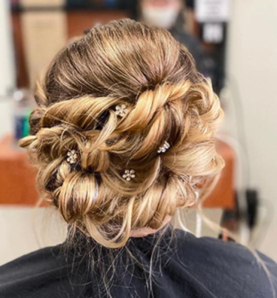 Intricate updo hairstyle with decorative flower pins in a Hair Cuttery location. Image links to Hair Cuttery's Instagram account.